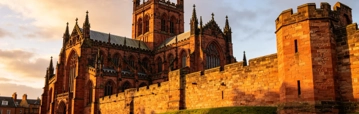 Historic cathedral and stone castle walls glowing in warm evening sunlight.