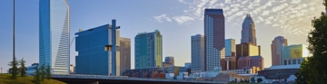 Modern city skyline with tall buildings under a bright sky.