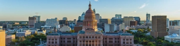 City skyline centred on a domed government building beneath a clear blue sky.